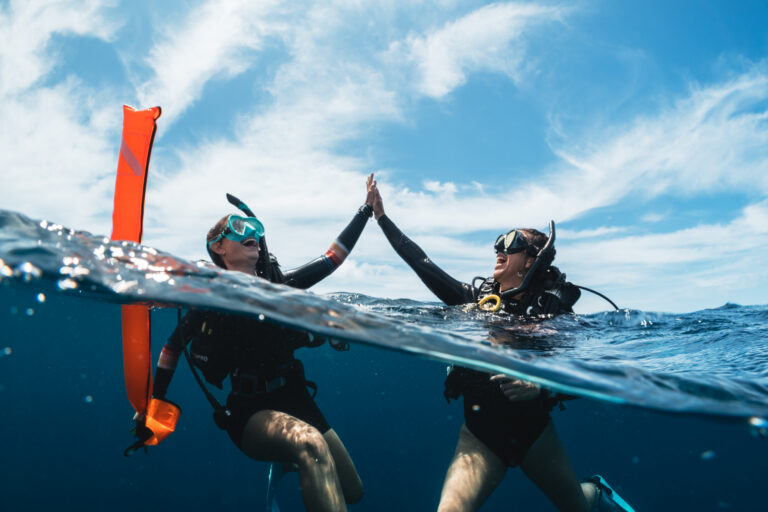 Two divers on the surface with a Delayed Surface Marker Buoy DSMB